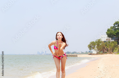 Beautiful women in bikinis strolling happily along the beach.