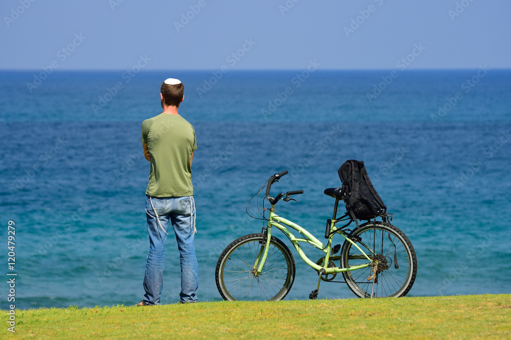 Fototapeta premium Lonely jewish man standing on the sea shore, looking at the horizon and thinking. 