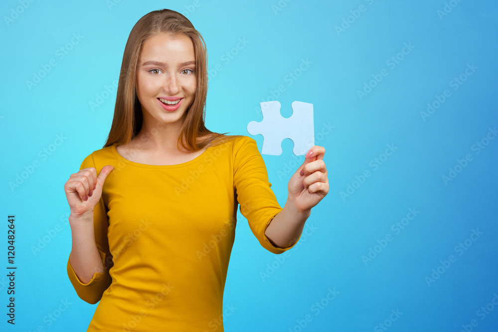 Beautiful young business woman holding a blue puzzle piece Beautiful young business woman holding a blue puzzle piece