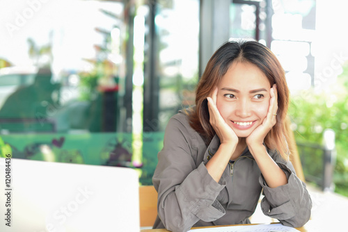 Overworked young woman sitting at the desk and holding his head