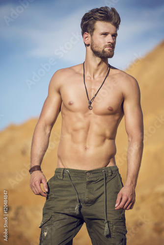 Handsome well-built man walking in the desert