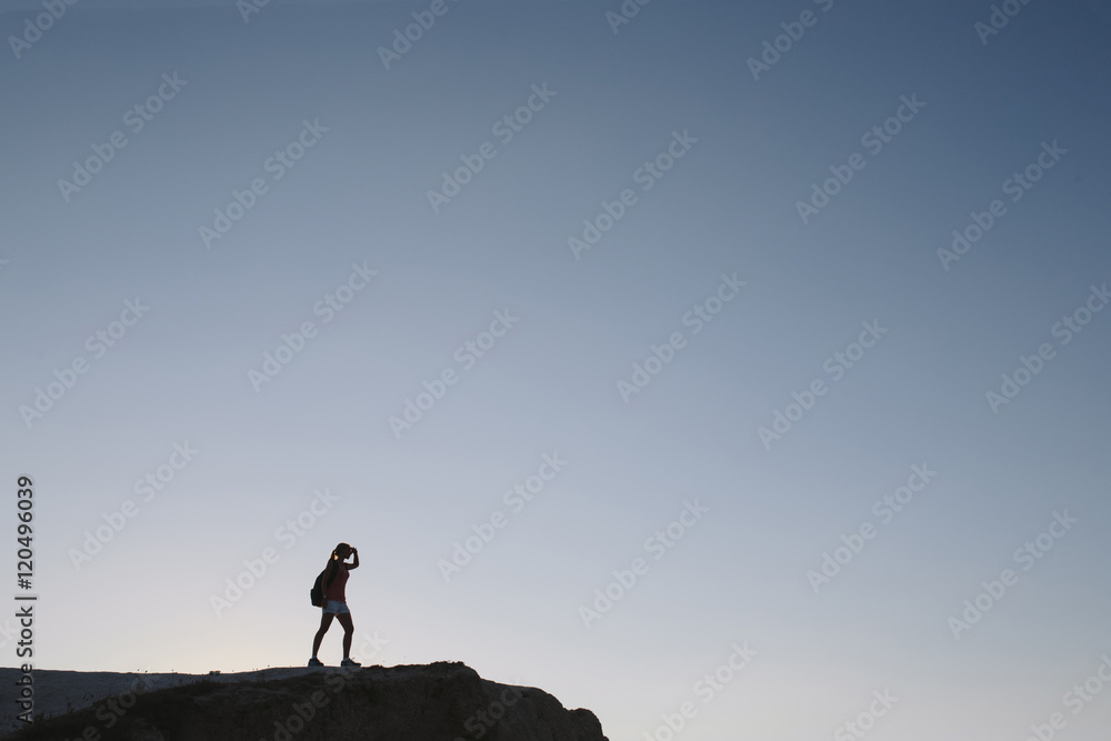 silhouette young woman tourist with backpack standing on cliff