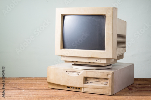 old and obsolete computer on old wood table with concrete wall background