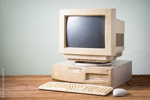 old and obsolete computer on old wood table with concrete wall background photo