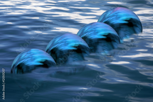 3d esferas azules sumergiéndose en el mar photo