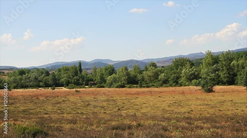 Paisaje de monte. Zona llana en primer plano, Soto en ribera de rio y colinas bosques o montañas al fondo
 photo