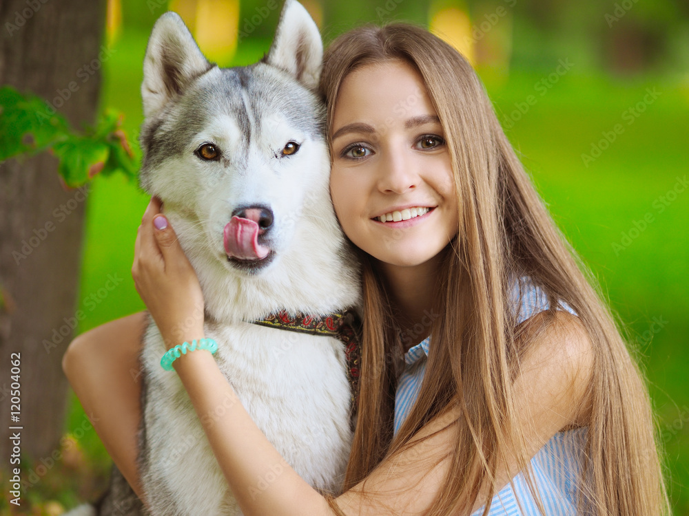 Attractive young woman hugs funny siberian husky dog who shows its tongue Attractive young woman hugs funny siberian husky dog who shows its tongue