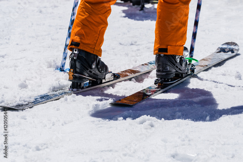 Man legs wear snowshoes and orange trousers stand on snow