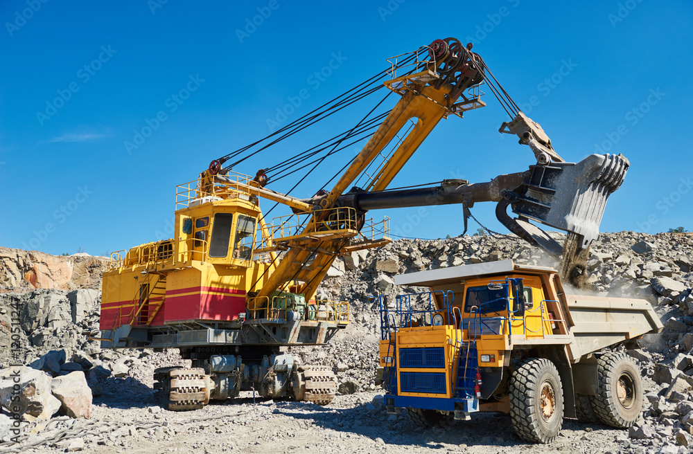 excavator loading granite or ore into dump truck at opencast