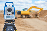surveyor equipment theodolie at construction site with excavator