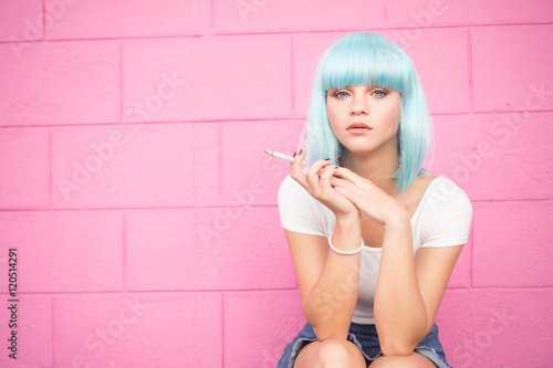 Valokuva Sexy young girl in modern futuristic style with blue wig and cigarette crouching