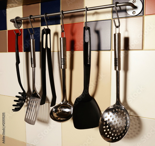 Kitchen utensils hanging on a colored tile wall