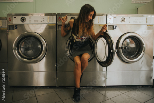 Young woman sitting in open door of laundromat photo