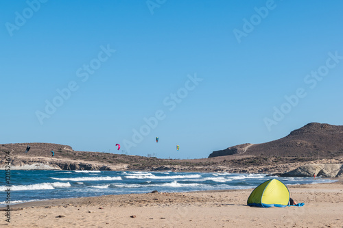 beach tent on sand, kitesurfers in backgroud