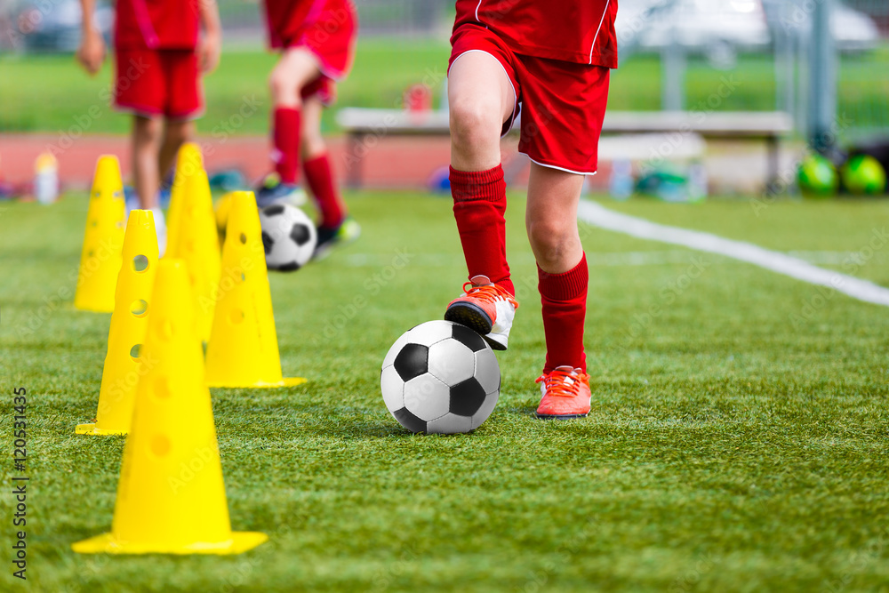 Soccer football players during the team training before the match. Exercises for football soccer youth team. Young player exercises with ball and marker cones Soccer football players during the team training before the match. Exercises for football soccer youth team. Young player exercises with ball and marker cones