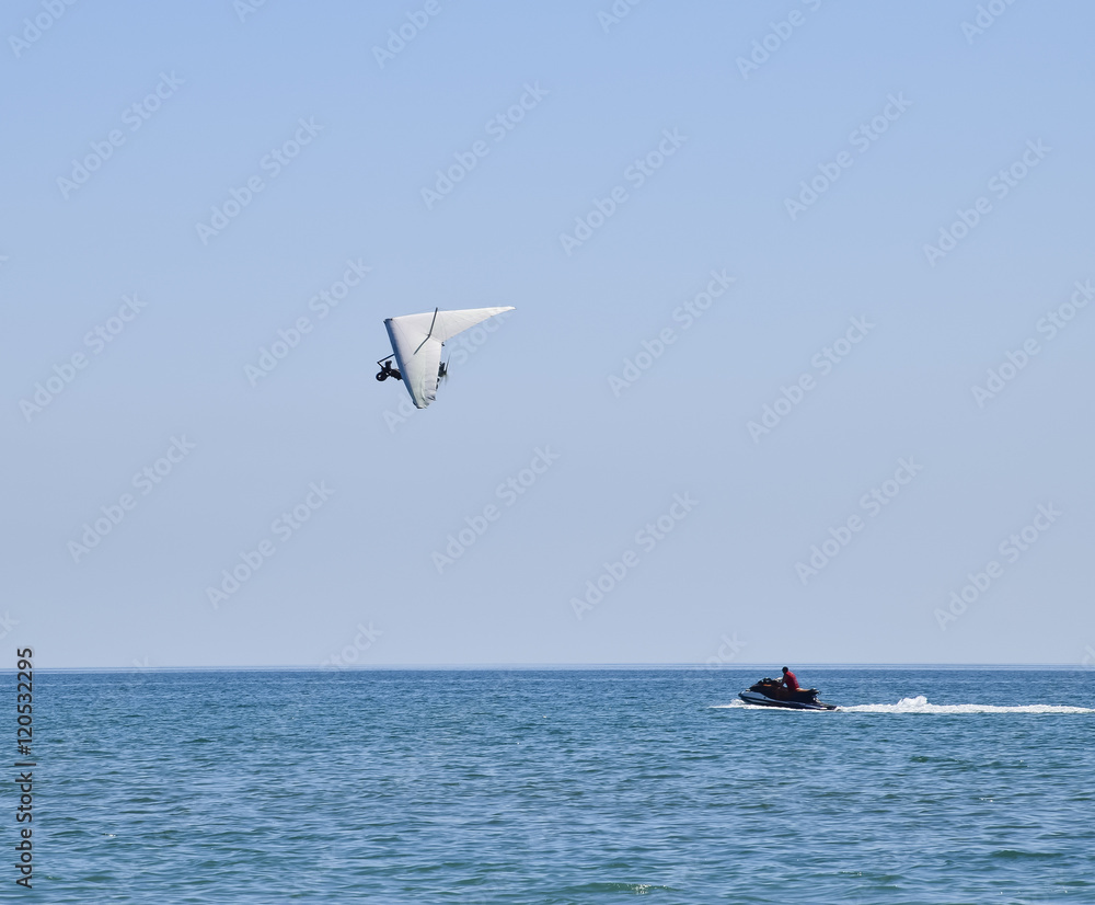 hang-gliding with the motor flies past a water scooter. Trike, flying in the sky with two people. Extreme Entertainment travelers.