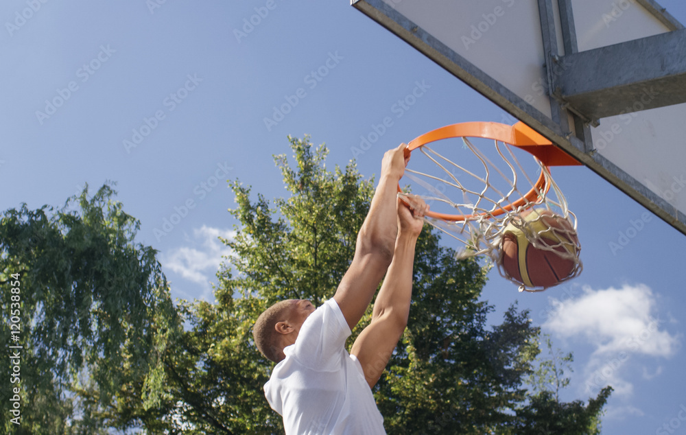 Obraz premium Basketball player slam dunking on an exterior court
