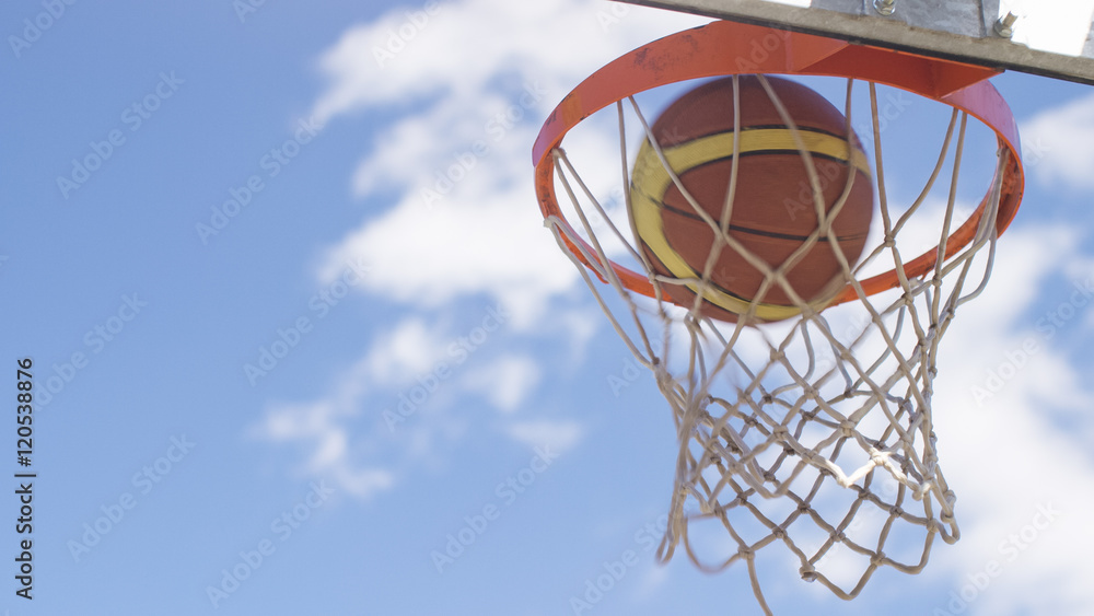 Basketball passing through the hoop and net on an outdoor court Basketball passing through the hoop and net on an outdoor court