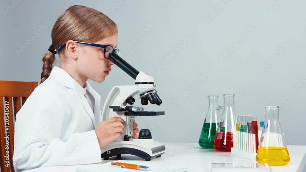 Portrait in profile young chemist 7-8 years using microscope and smiling at camera. Isolated on white Portrait in profile young chemist 7-8 years using microscope and smiling at camera. Isolated on white