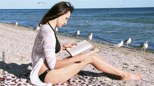 Young woman reading a book on the beach. photo