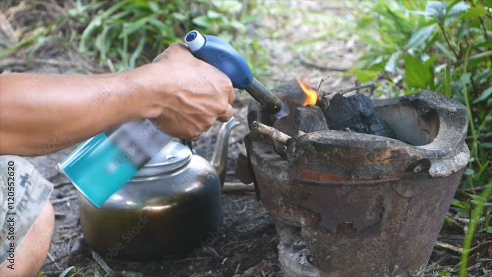 Man lighting charcol in stove by using flame gas Man lighting charcol in stove by using flame gas