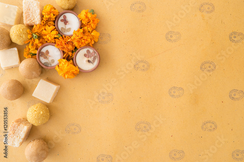 Diwali prayer celebration preparation with sweets and diyas and marigold flowers on handmade paper with Indian motifs with copy space photo