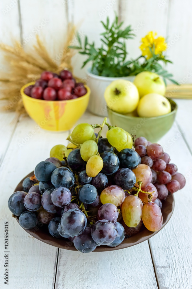 Freshly picked grapes in several varieties of clay bowl on a light background. Freshly picked grapes in several varieties of clay bowl on a light background.