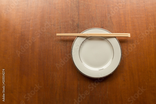 chopsticks with white dish on wood table with copy space.