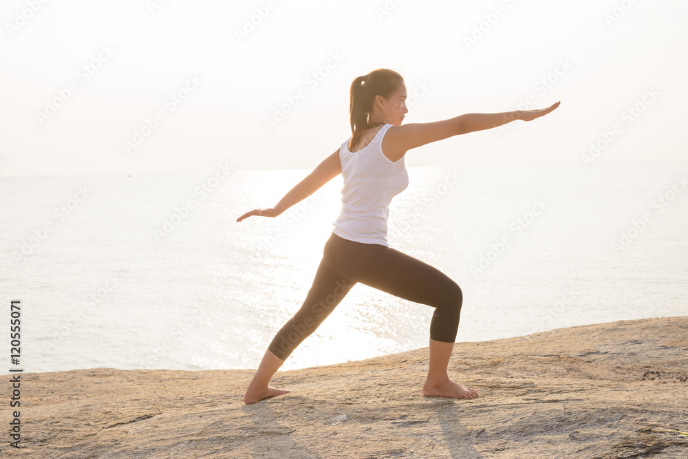 Woman practicing Warrior yoga pose on the beach Woman practicing Warrior yoga pose on the beach