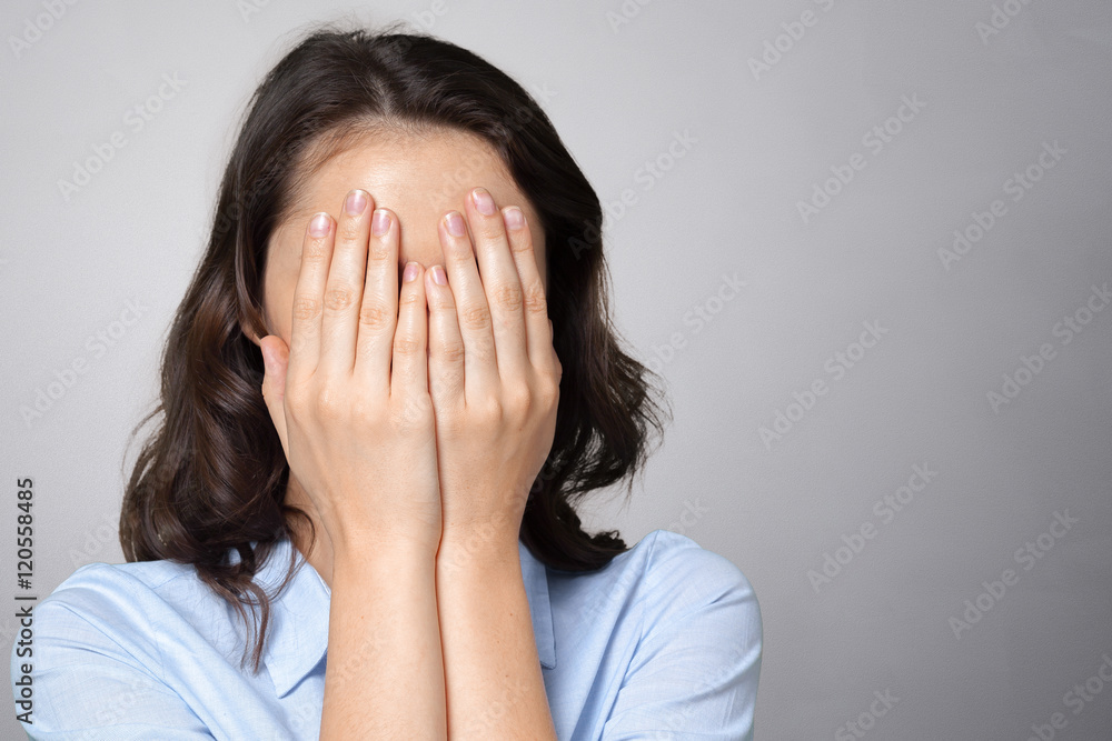 Woman covering her face with both hands Woman covering her face with both hands
