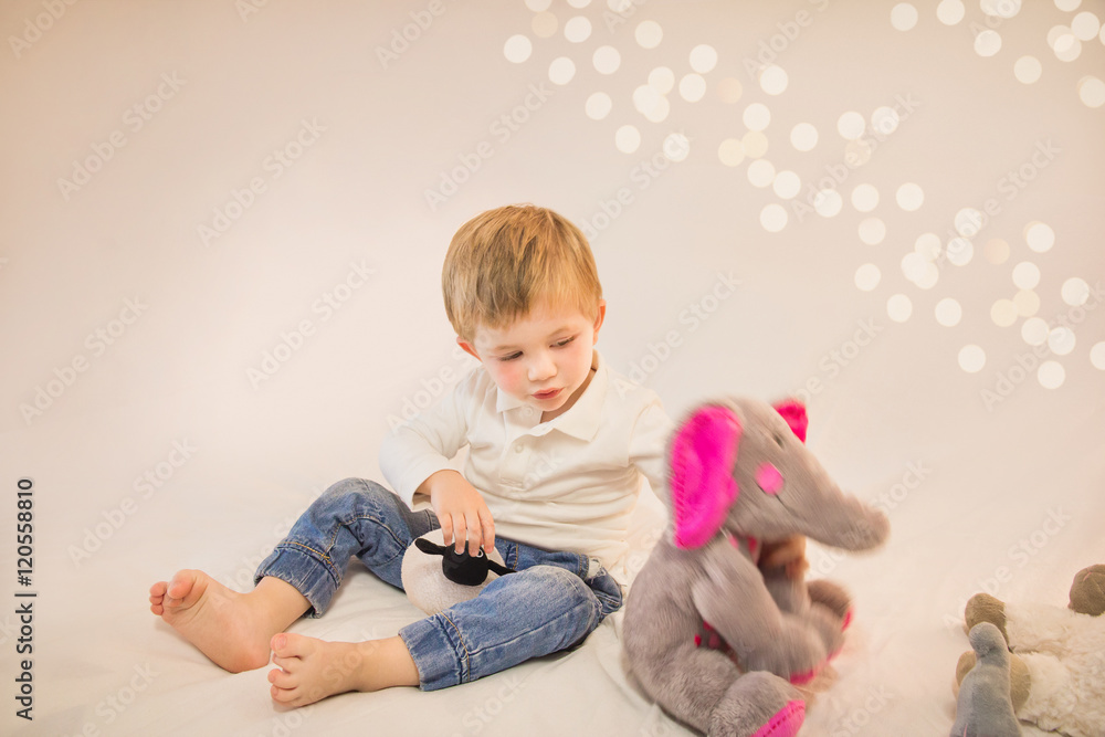 Naklejka premium Adorable little boy playing with his favourite stuffed animals