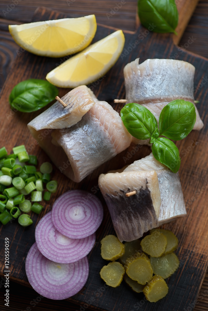 Herring fillet rolls with onion, gherkins and lemon, close-up