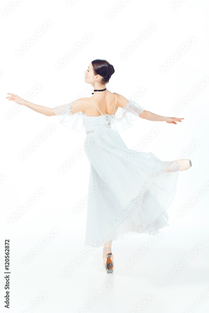Naklejka premium Ballerina in white dress posing on pointe shoes, studio background.