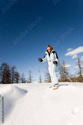 woman hiking with snowshoes in a clear sky day