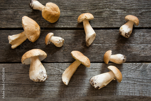 Fresh white mushrooms from forest on a rustic wooden board, overhead view.