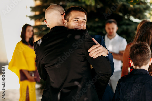 Groom on his wedding day hugging relatives