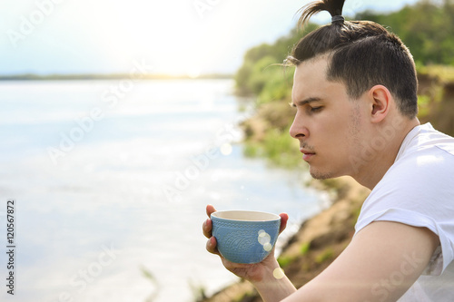 Fotografía Young man drinking coffee on the beach in Sunny summer day