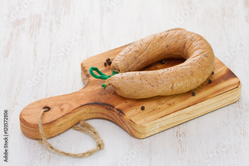smoked portuguese sausage alheira on wooden board on white background photo