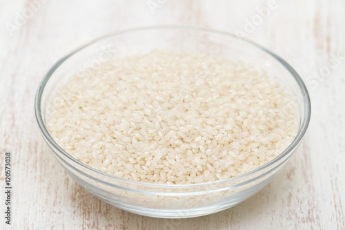 raw rice in bowl on white wooden background