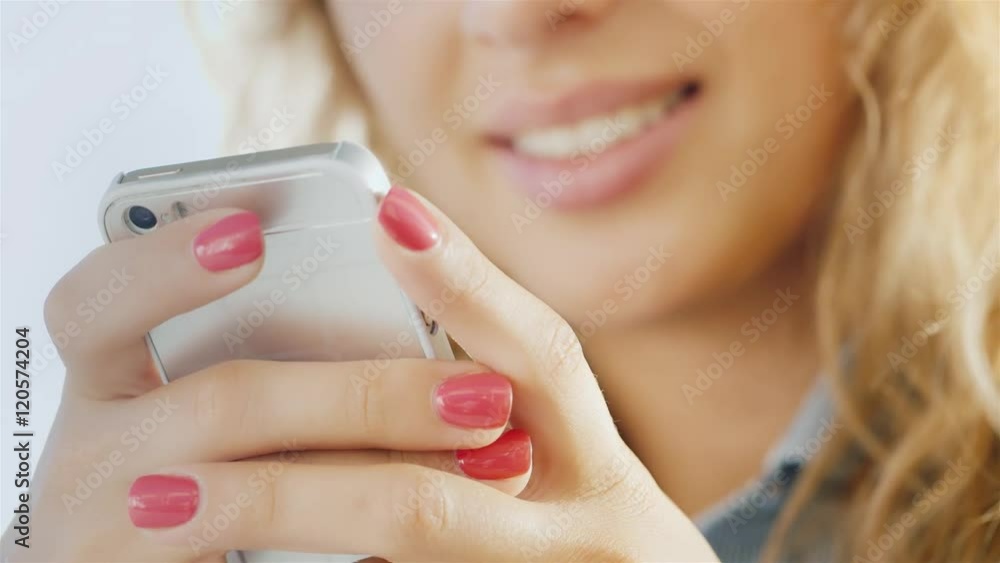 Hands of a young woman with a mobile phone, smiling lips slightly blurred Hands of a young woman with a mobile phone, smiling lips slightly blurred