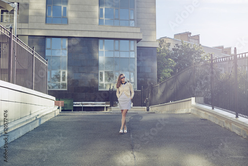 Beautiful Europian girl or woman in casual wear walking in the modern city in sunny weather and summer or autumn day.