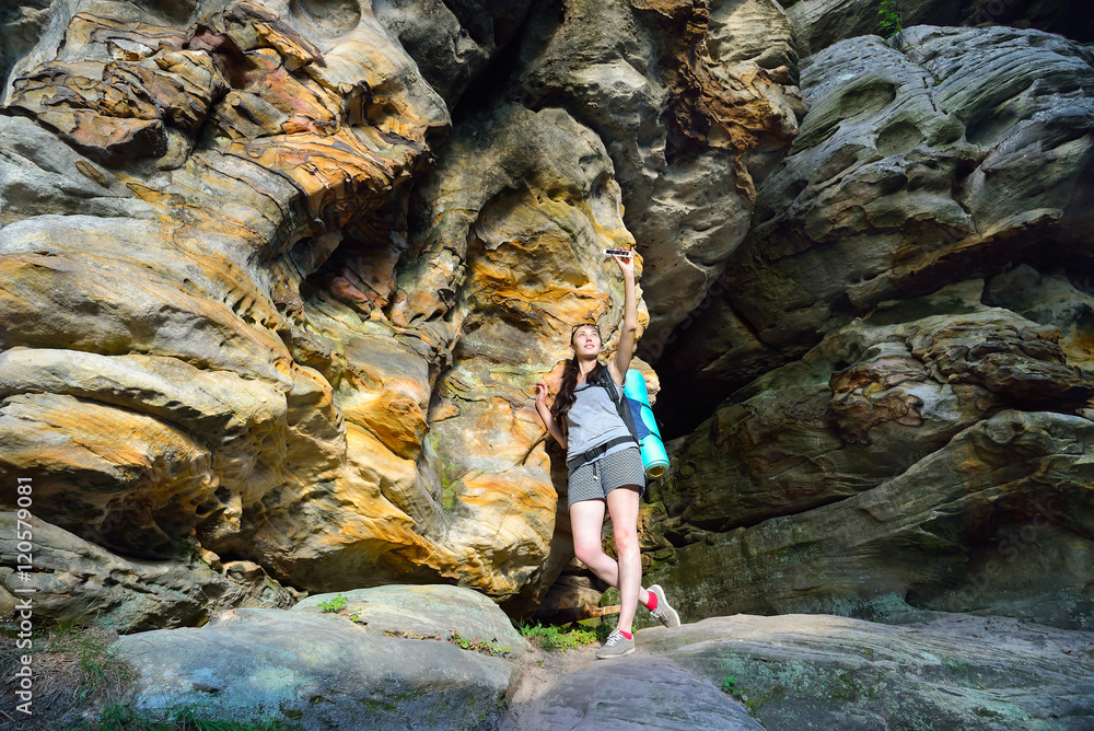 Woman Hiker with backpack exploring beautiful colorful canyon, and making photo on smartphone