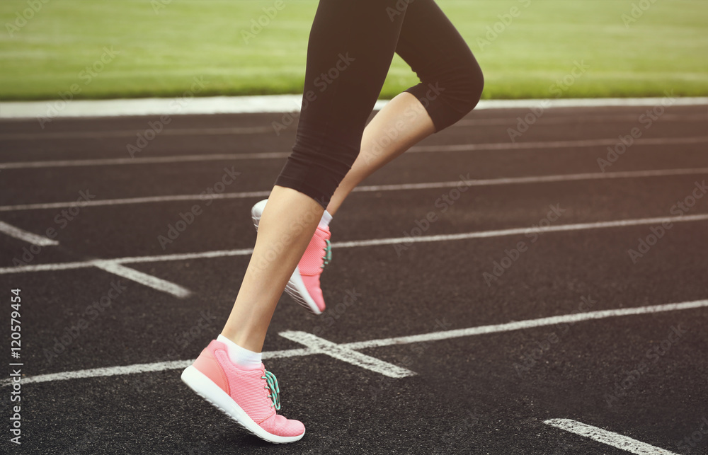 Woman running in pink sneakers on a stadium