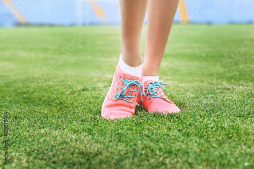 Woman wearing pink sneakers and standing on a grass © Africa Studio