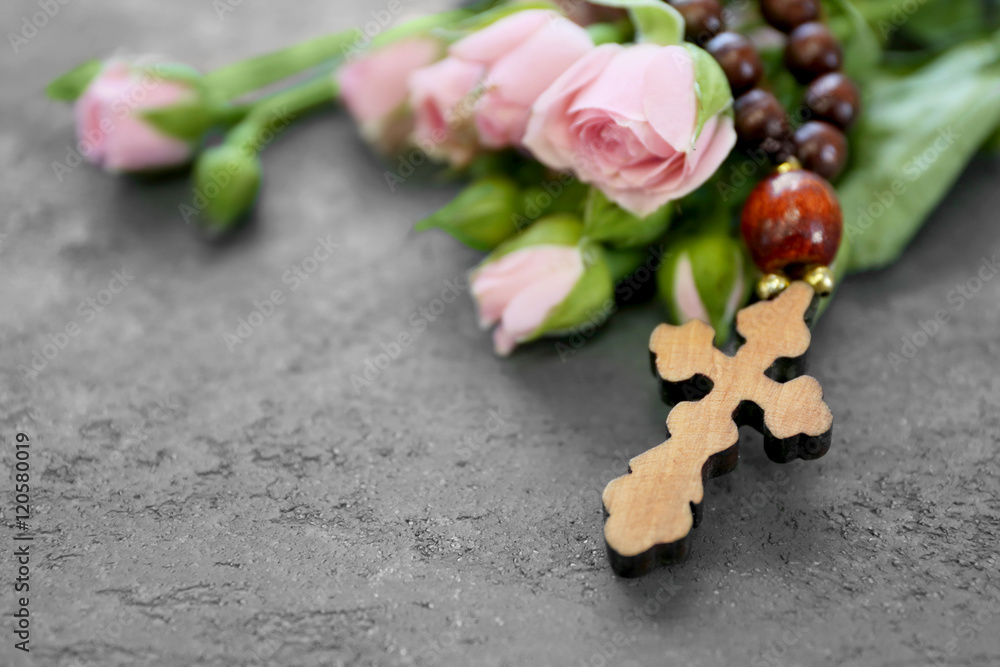 Wooden cross with flowers on grey textured background