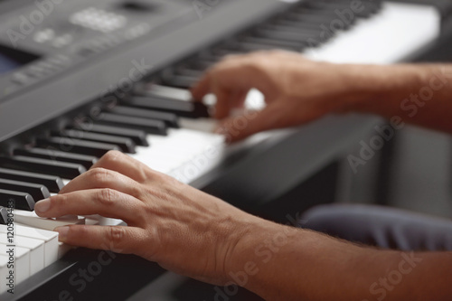 Male hands playing on synthesizer