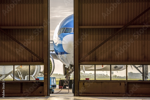 Foto Airplane in front of half opened door to hangar