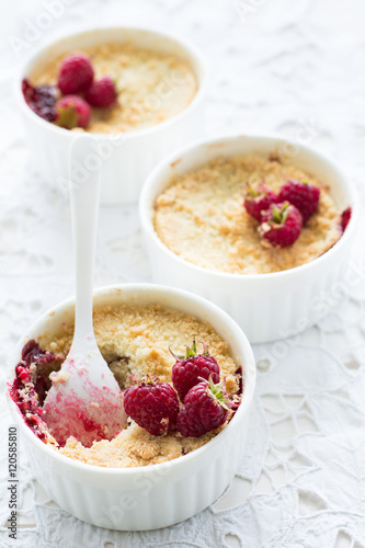 Homemade raspberry crumble on white wooden background