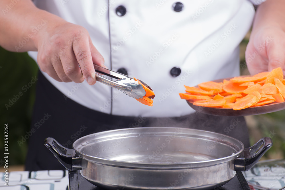 Chef putting carrot for cooking