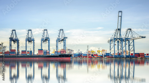 Fotografie, Tablou International Container Cargo ship with working crane bridge in shipyard background, logistic import export background and transport industry